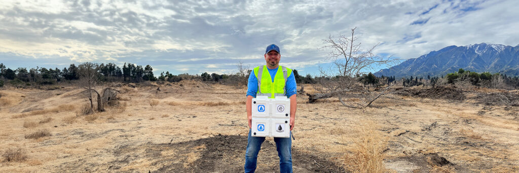 Owner Ed Seichei stands in an open field holding two Aquablocks.